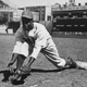 Jackie Robinson (1919 - 1972) grounds a ball at first place while warming up for an exhibition game against the New York Yankees, Ebbets Field, NYC, 1950s.